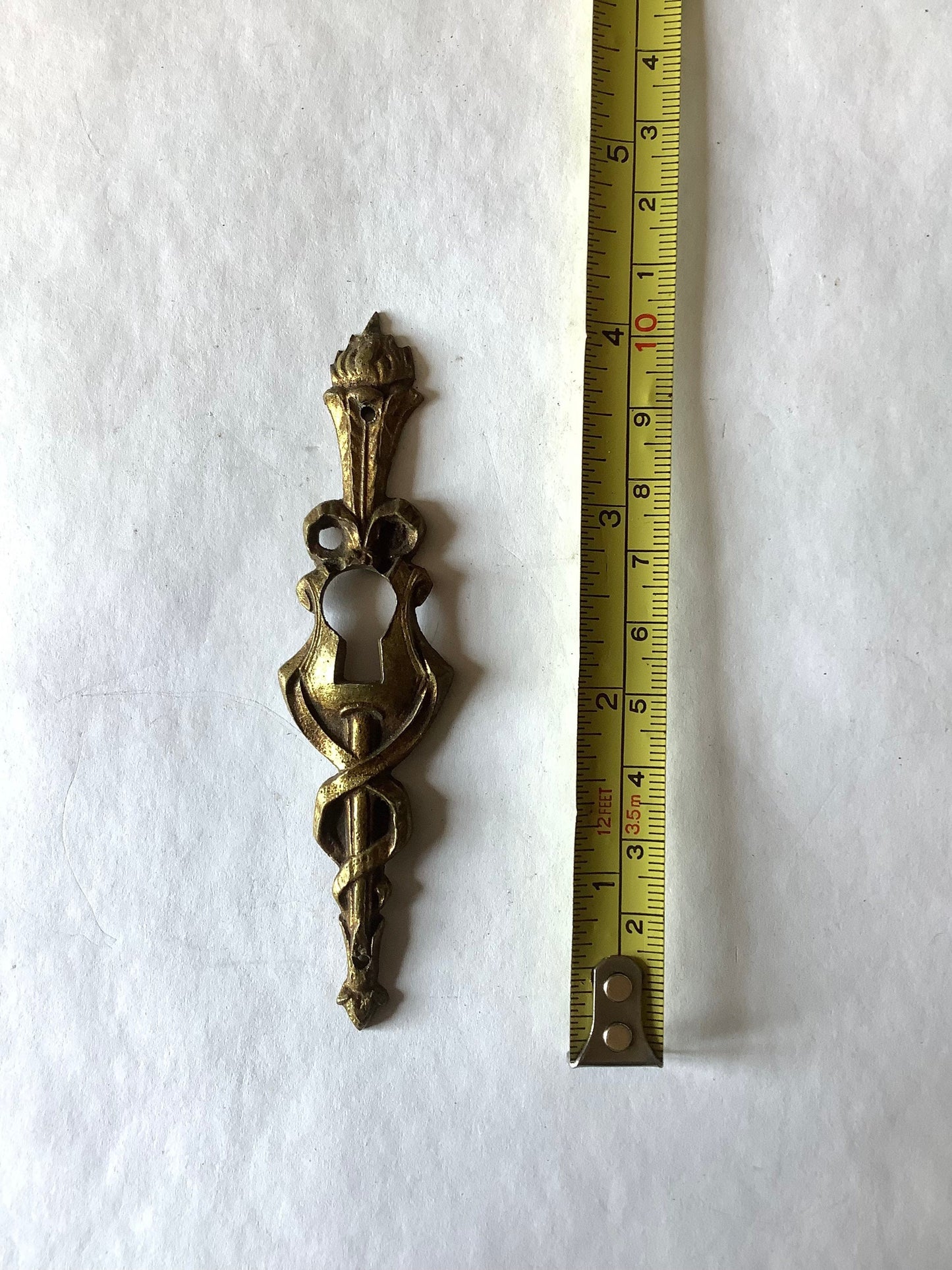 One Antique Brass Ormolu Keyhole Cover Escutcheon made in France in the 1920s elegant torch insignia